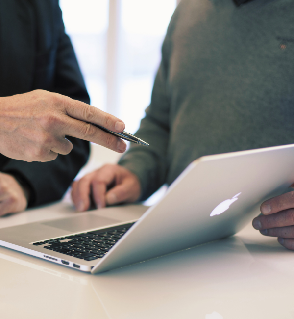 Two colleagues review information on a laptop.